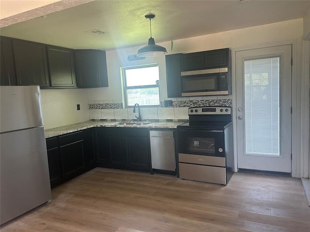 5326 NW Columbia Ave, Lawton, OK 73505 - kitchen featuring stainless steel appliances, light stone counters, light wood-style floors, tasteful backsplash, and pendant lighting