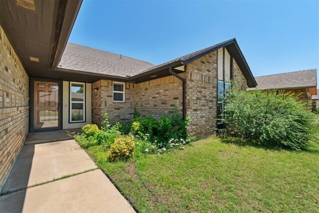 708 Cactus Ct, Yukon, OK 73099 - doorway to property with a lawn, brick siding, and a shingled roof