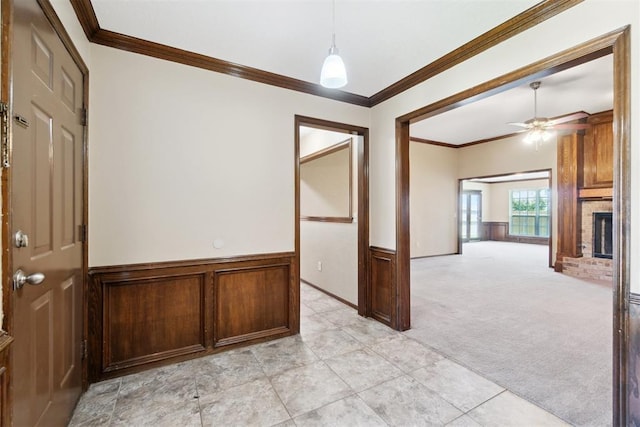 708 Cactus Ct, Yukon, OK 73099 - unfurnished room with light colored carpet, a wainscoted wall, ornamental molding, a brick fireplace, and a ceiling fan