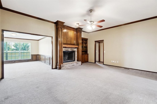 708 Cactus Ct, Yukon, OK 73099 - unfurnished living room with ceiling fan, a fireplace, light carpet, ornamental molding, and a wainscoted wall