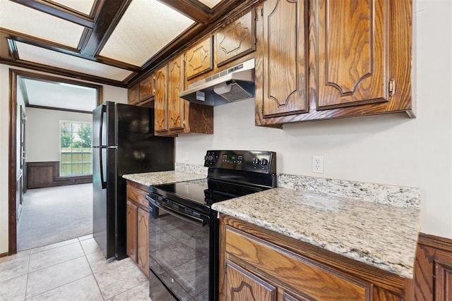708 Cactus Ct, Yukon, OK 73099 - kitchen with black appliances, under cabinet range hood, light carpet, brown cabinets, and a wainscoted wall