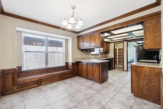 708 Cactus Ct, Yukon, OK 73099 - kitchen featuring a chandelier, a peninsula, crown molding, a wainscoted wall, and light tile patterned flooring