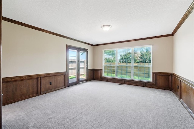 708 Cactus Ct, Yukon, OK 73099 - spare room featuring a wainscoted wall, light carpet, a textured ceiling, and crown molding