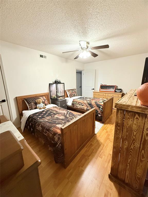 1616 NE 5th St, Moore, OK 73160 - bedroom featuring light wood-style flooring, a textured ceiling, and ceiling fan