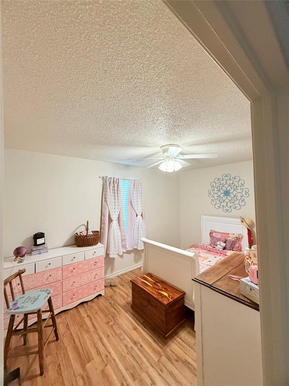 1616 NE 5th St, Moore, OK 73160 - bedroom featuring light wood-style floors, a textured ceiling, and ceiling fan