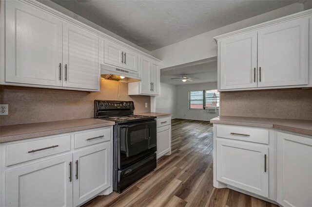 406 SW 4th St, Tuttle, OK 73089 - kitchen featuring electric range, under cabinet range hood, wood finished floors, and white cabinetry