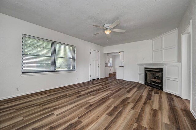 406 SW 4th St, Tuttle, OK 73089 - unfurnished living room featuring a ceiling fan, dark wood finished floors, a fireplace, and a textured ceiling