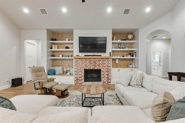 5017 Yale Bridge Ct, Edmond, OK 73034 - living room with light wood-style floors, arched walkways, recessed lighting, and a fireplace