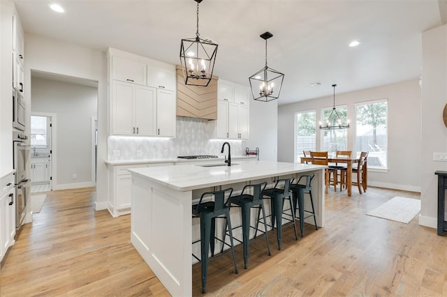 5017 Yale Bridge Ct, Edmond, OK 73034 - kitchen with a chandelier, tasteful backsplash, recessed lighting, a kitchen island with sink, and a kitchen bar