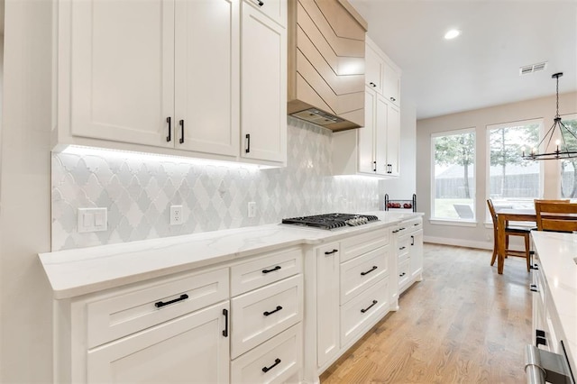 5017 Yale Bridge Ct, Edmond, OK 73034 - kitchen with stainless steel gas stovetop, premium range hood, a chandelier, decorative backsplash, and recessed lighting