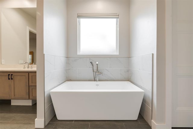 5017 Yale Bridge Ct, Edmond, OK 73034 - bathroom featuring vanity, a soaking tub, tile patterned floors, and tile walls
