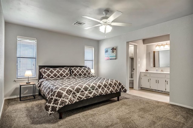 1713 Shadow Ct, Edmond, OK 73013 - bedroom with light carpet, multiple windows, ceiling fan, and connected bathroom