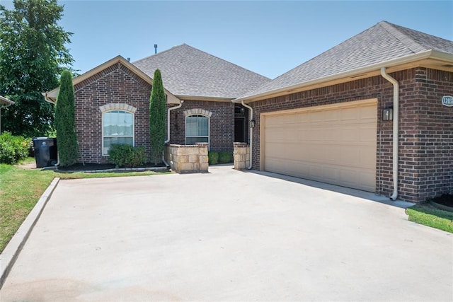 12037 Ashford Dr, Yukon, OK 73099 - french country inspired facade featuring brick siding, a shingled roof, a garage, and driveway