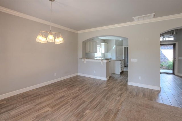 12037 Ashford Dr, Yukon, OK 73099 - unfurnished living room featuring wood finished floors, a chandelier, arched walkways, and ornamental molding