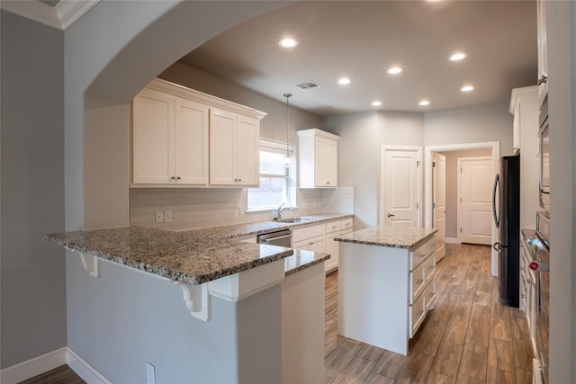 12037 Ashford Dr, Yukon, OK 73099 - kitchen with appliances with stainless steel finishes, a peninsula, recessed lighting, light stone counters, and arched walkways