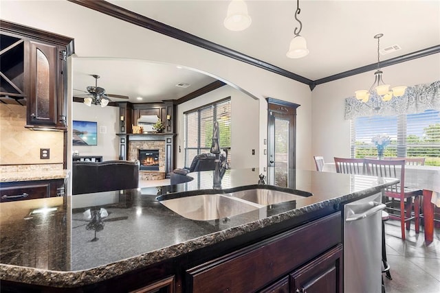 126 Castle Gate Dr, Choctaw, OK 73020 - kitchen featuring crown molding, arched walkways, a fireplace, and dark brown cabinetry