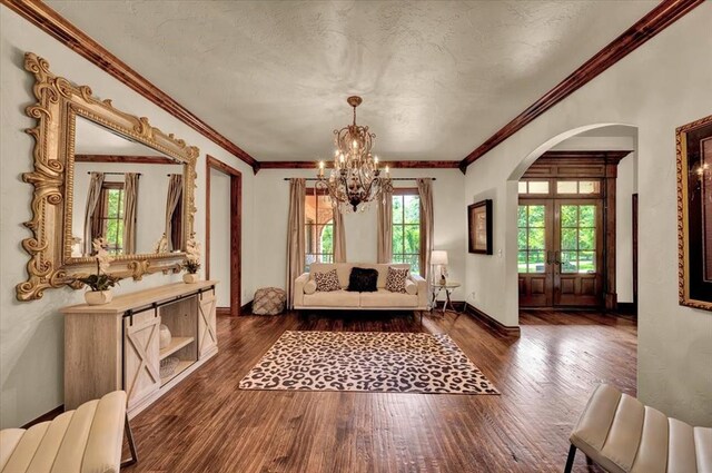 10035 Stone Gate Way, Arcadia, OK 73007 - living area featuring arched walkways, a chandelier, dark wood-style floors, ornamental molding, and a textured ceiling