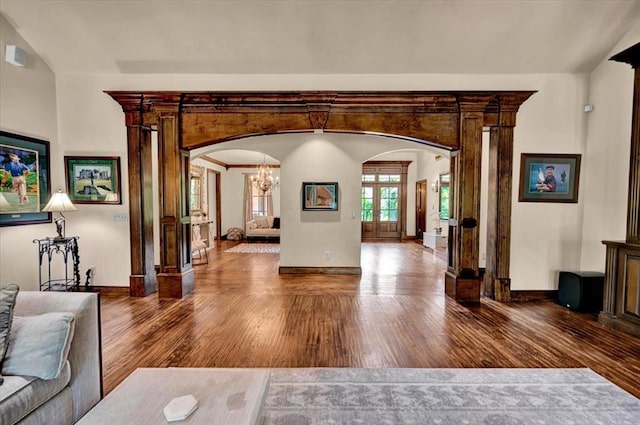 10035 Stone Gate Way, Arcadia, OK 73007 - unfurnished living room with arched walkways, ornate columns, wood finished floors, a chandelier, and lofted ceiling