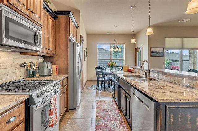 412 Swingman Rd, Yukon, OK 73099 - kitchen with appliances with stainless steel finishes, backsplash, brown cabinets, a chandelier, and light stone counters