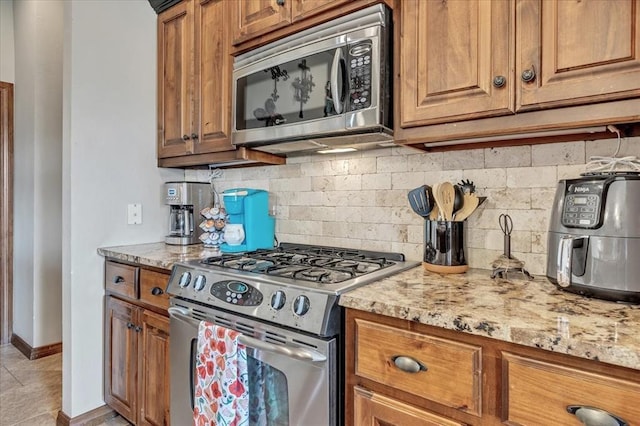 412 Swingman Rd, Yukon, OK 73099 - kitchen with stainless steel appliances, backsplash, brown cabinetry, and light stone countertops