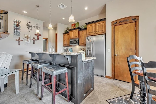 412 Swingman Rd, Yukon, OK 73099 - kitchen with stainless steel appliances, a breakfast bar area, brown cabinetry, light stone counters, and decorative backsplash