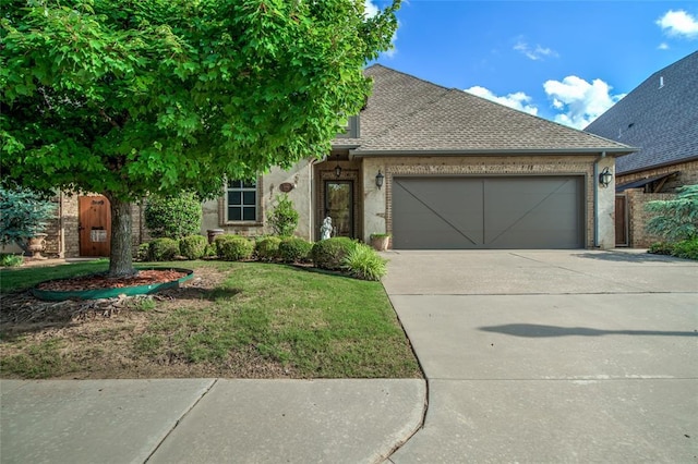 2216 SW 117th St, Oklahoma City, OK 73170 - view of front of home featuring a garage, concrete driveway, roof with shingles, brick siding, and a front yard