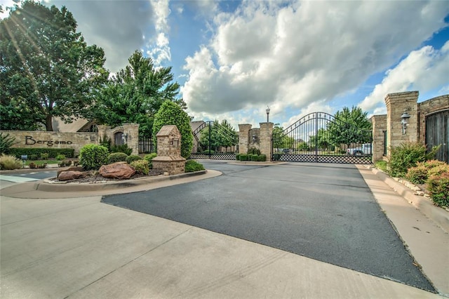 2216 SW 117th St, Oklahoma City, OK 73170 - view of asphalt road featuring a gate, a gated entry, and curbs