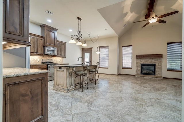 2216 SW 117th St, Oklahoma City, OK 73170 - kitchen featuring stainless steel appliances, a breakfast bar area, plenty of natural light, open floor plan, and high vaulted ceiling