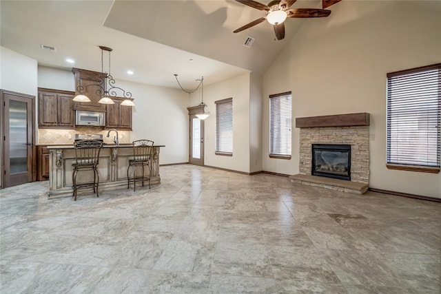2216 SW 117th St, Oklahoma City, OK 73170 - kitchen featuring stainless steel appliances, open floor plan, a ceiling fan, a kitchen breakfast bar, and a fireplace