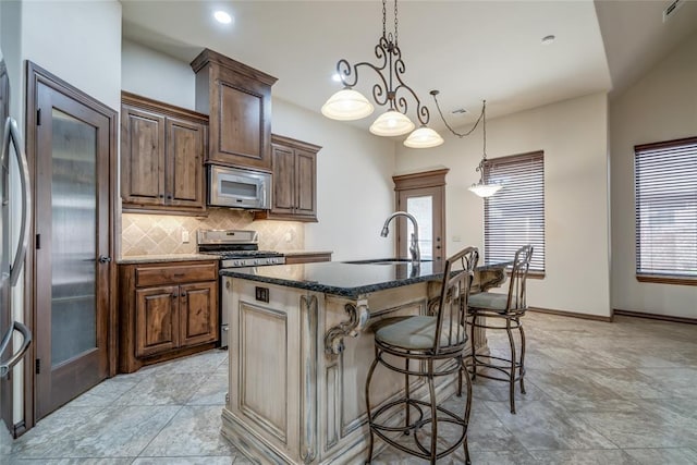 2216 SW 117th St, Oklahoma City, OK 73170 - kitchen with stainless steel appliances, decorative backsplash, an island with sink, a kitchen breakfast bar, and dark stone countertops
