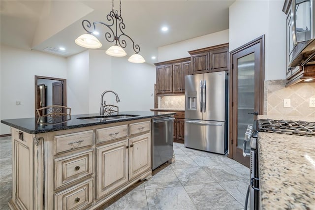 2216 SW 117th St, Oklahoma City, OK 73170 - kitchen with stainless steel appliances, decorative backsplash, a center island with sink, dark stone countertops, and decorative light fixtures