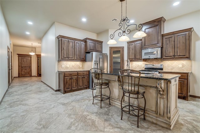 2216 SW 117th St, Oklahoma City, OK 73170 - kitchen featuring appliances with stainless steel finishes, decorative backsplash, dark stone counters, a breakfast bar, and decorative light fixtures