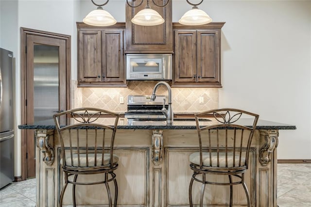 2216 SW 117th St, Oklahoma City, OK 73170 - kitchen with appliances with stainless steel finishes, dark stone counters, a breakfast bar, decorative backsplash, and a center island with sink