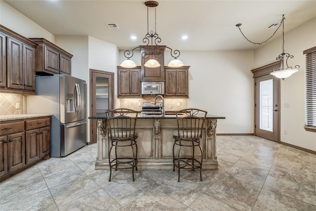 2216 SW 117th St, Oklahoma City, OK 73170 - kitchen with stainless steel appliances, dark stone counters, a kitchen bar, decorative backsplash, and recessed lighting