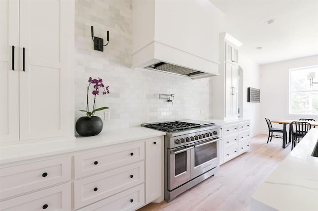 416 Old Creek Rd, Edmond, OK 73034 - kitchen featuring range with two ovens, custom exhaust hood, tasteful backsplash, white cabinets, and light wood-style flooring
