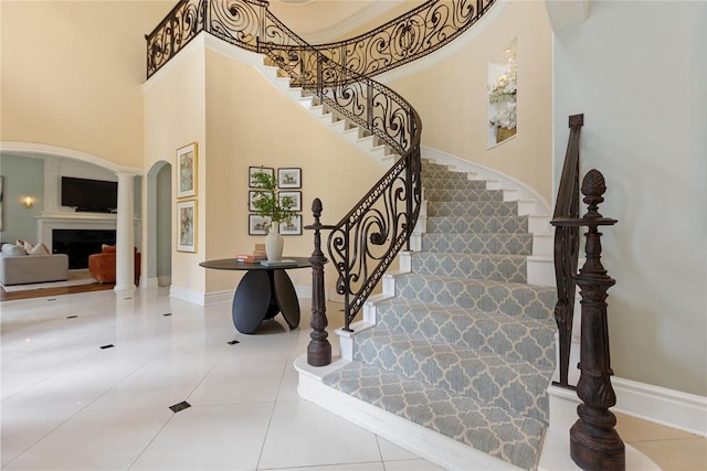 4800 Bocage Pl, Oklahoma City, OK 73142 - stairs with tile patterned flooring, a fireplace, arched walkways, a high ceiling, and decorative columns