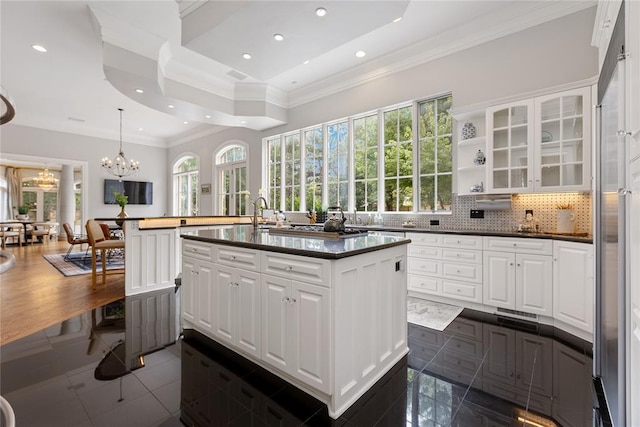 4800 Bocage Pl, Oklahoma City, OK 73142 - kitchen with a chandelier, dark countertops, crown molding, a kitchen island with sink, and white cabinetry