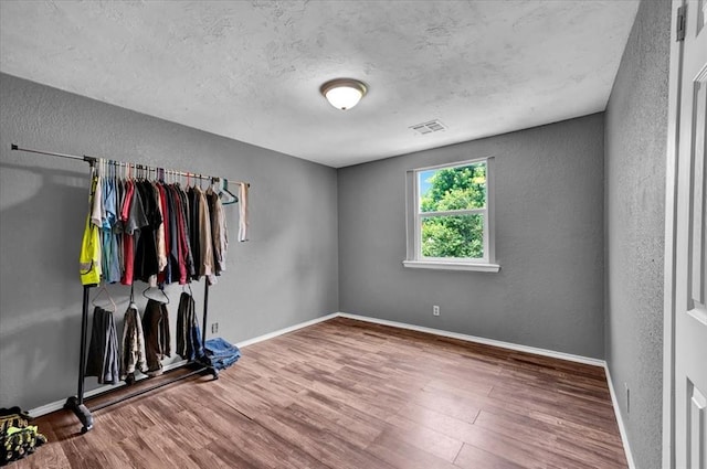 1017 Linn Ln, Yukon, OK 73099 - unfurnished bedroom featuring wood finished floors, a textured ceiling, and a textured wall