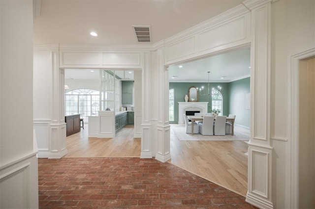 305 Carmel Valley Way, Edmond, OK 73025 - corridor with ornate columns, a decorative wall, crown molding, and brick floors