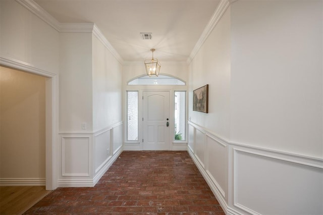 305 Carmel Valley Way, Edmond, OK 73025 - foyer featuring a chandelier, brick floors, a decorative wall, a wainscoted wall, and ornamental molding