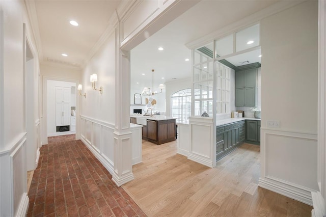 305 Carmel Valley Way, Edmond, OK 73025 - corridor with a decorative wall, ornamental molding, a chandelier, wainscoting, and decorative columns