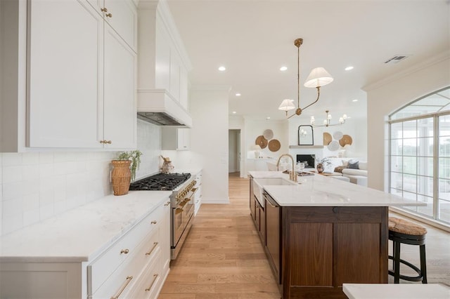305 Carmel Valley Way, Edmond, OK 73025 - kitchen with range with two ovens, light wood finished floors, healthy amount of natural light, ornamental molding, and open floor plan