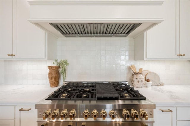 305 Carmel Valley Way, Edmond, OK 73025 - kitchen view of range hood, stove, white cabinets, and tasteful backsplash