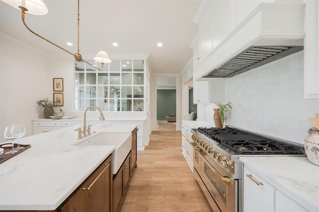 305 Carmel Valley Way, Edmond, OK 73025 - kitchen with premium range hood, stainless steel stove, light wood-style flooring, white cabinetry, and ornamental molding