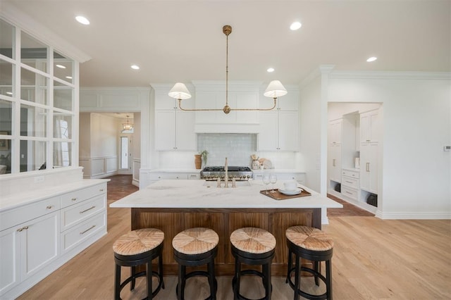 305 Carmel Valley Way, Edmond, OK 73025 - kitchen featuring crown molding, decorative backsplash, a breakfast bar area, light wood-style floors, and white cabinets