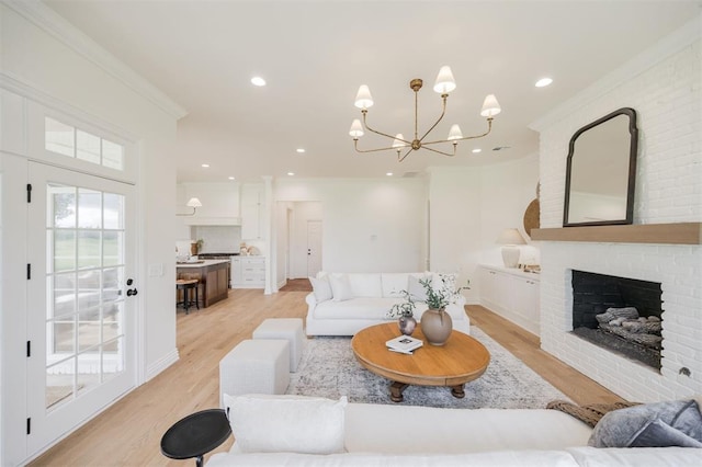 305 Carmel Valley Way, Edmond, OK 73025 - living room featuring crown molding, light wood-style floors, a chandelier, recessed lighting, and a brick fireplace