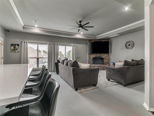 7821 Lindsay Ln, Edmond, OK 73025 - living area featuring a tray ceiling, finished concrete floors, a ceiling fan, a stone fireplace, and recessed lighting
