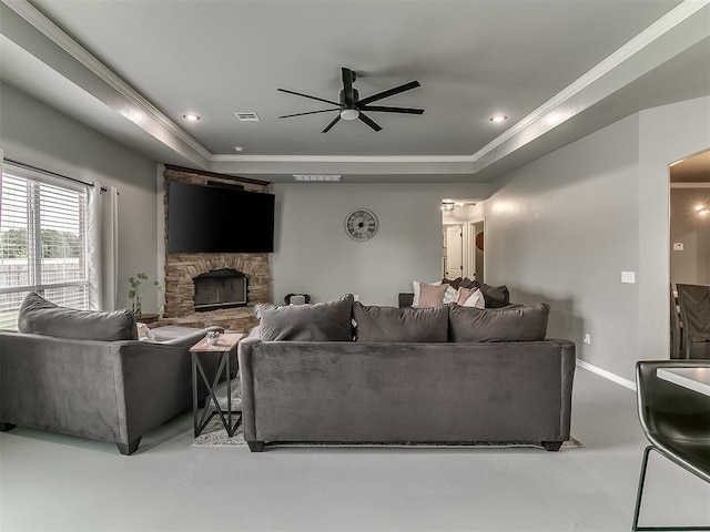 7821 Lindsay Ln, Edmond, OK 73025 - living room featuring a tray ceiling, a ceiling fan, a fireplace, crown molding, and finished concrete flooring