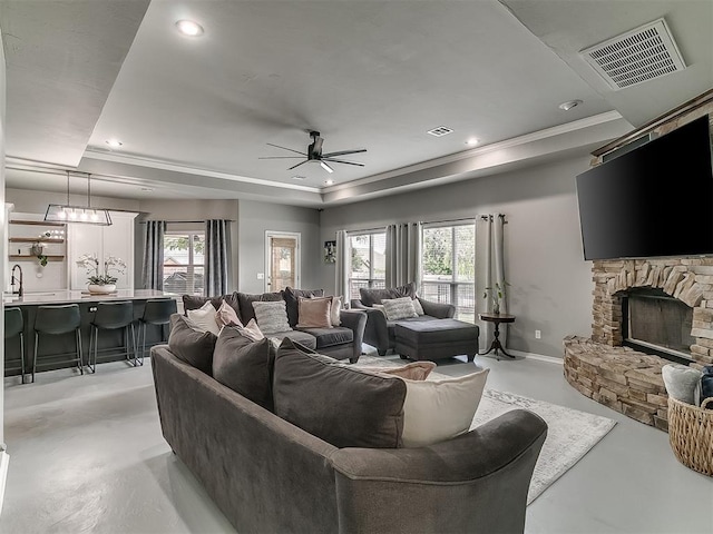 7821 Lindsay Ln, Edmond, OK 73025 - living room featuring a tray ceiling, concrete floors, healthy amount of natural light, a ceiling fan, and recessed lighting