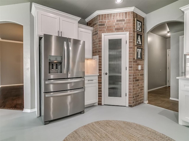 7821 Lindsay Ln, Edmond, OK 73025 - kitchen featuring stainless steel fridge with ice dispenser, arched walkways, white cabinetry, light countertops, and ornamental molding